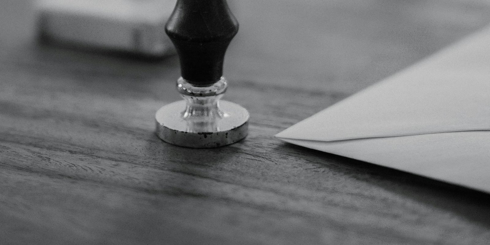 An official seal resting on a desk beside a sealed envelope
